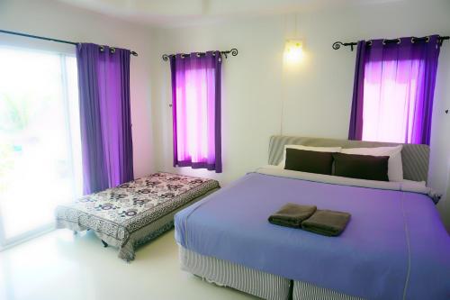 格兰岛Thongtalay Bed & Breakfast Koh Larn的一间卧室配有紫色窗帘和一张大床