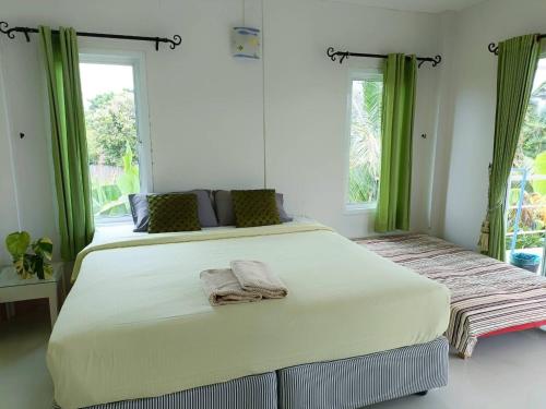 格兰岛Thongtalay Bed & Breakfast Koh Larn的卧室配有带绿色窗帘的大型白色床