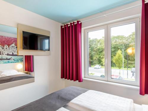 吕讷堡鲁纳堡B＆B酒店的一间卧室设有红色窗帘的窗户
