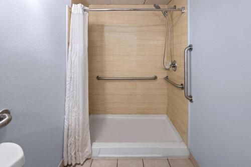 昆斯伯里昆斯伯里戴斯酒店的浴室内配有带白色浴缸的淋浴