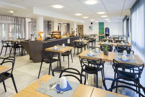 特里尼亚克Best Western Les Aureliades Saint Nazaire的餐厅设有木桌、椅子和柜台