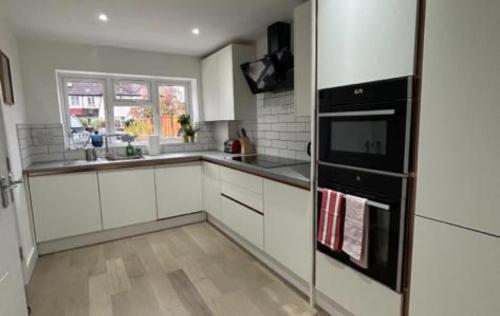 米查姆London Stunning Three Bedroom House的厨房配有白色橱柜和黑色冰箱。