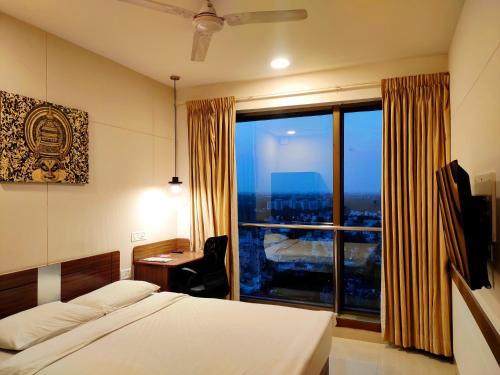 钦奈姜晨奈酒店的一间卧室配有一张床、一张书桌和一个大窗户