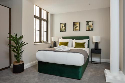 伦敦Chancery Lane by Viridian Apartments的一间卧室配有绿色和白色的床和植物