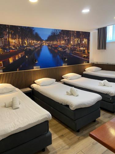 阿姆斯特丹提图斯城市中心酒店的一间设有三张床的房间和运河壁画