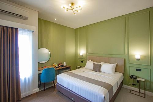 日惹Hotel FortunaGrande Malioboro Yogyakarta的一间卧室配有一张床、一张书桌和一个窗户。