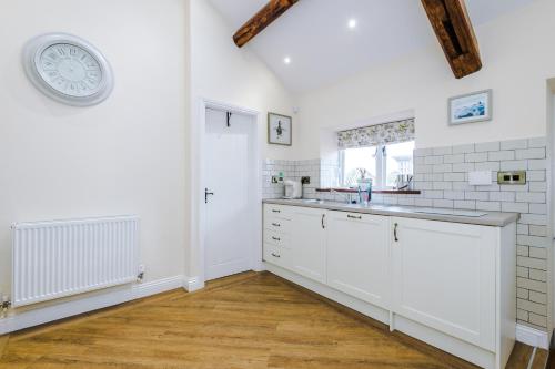 比斯顿Stunning 3-bed cottage in Beeston by 53 Degrees Property, ideal for Families & Groups, Great Location - Sleeps 6的厨房配有白色橱柜和墙上的时钟