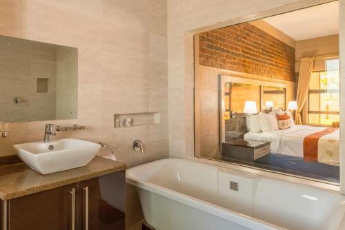 KingsmeadExquisite executive room for 2 - 2179的一间带水槽的浴室和一张带镜子的床