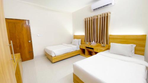 达卡Crown Palace Residence的酒店客房 - 带两张床、一张桌子和一张床