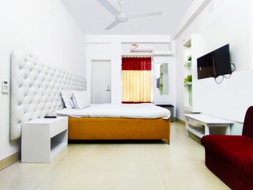 达卡White Rose Suites Ltd的一间卧室配有一张大床和一张红色的沙发