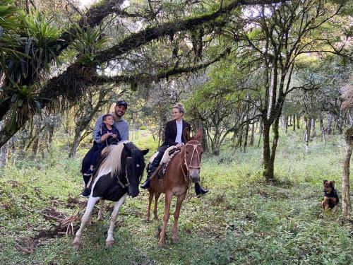 邦雅尔丁-达塞拉Chalés Recanto do Vale - GRALHA AZUL的一群人骑着马和狗一起骑着