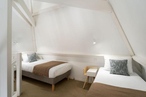 拉波勒Hôtel Miléade Les Pléïades La Baule的配有白色墙壁的小客房内的两张床