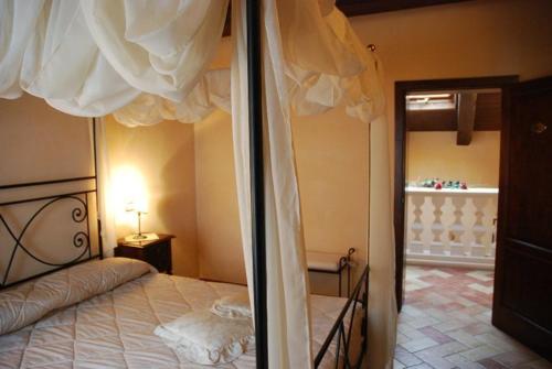 Urbisaglia罗卡达小屋酒店 的一间卧室配有天蓬床和镜子