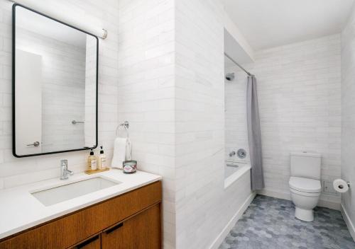 纽约Modern Studio Apartment At East Side的一间带水槽、卫生间和镜子的浴室