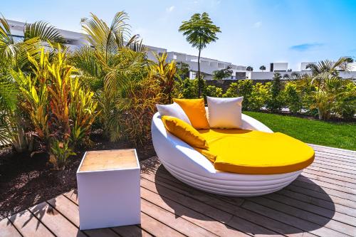 阿吉内金海滩Resort Cordial Santa Águeda & Perchel Beach Club的一张黄色和白色的床,坐在甲板上