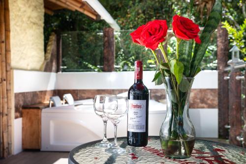 圣奥古斯丁Finca Ecológica El Maco的一瓶葡萄酒和两杯酒以及一瓶玫瑰花瓶