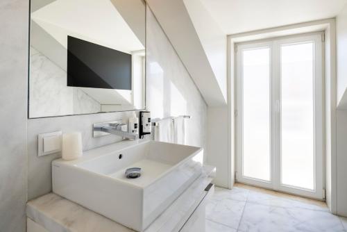 里斯本希亚多广场公寓 | 里斯本百斯特公寓的白色的浴室设有水槽和电视。
