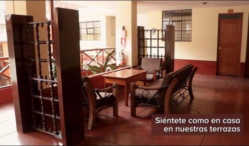ChalhuancaHOTEL ZEGARRA的客房设有木桌、椅子和桌椅。