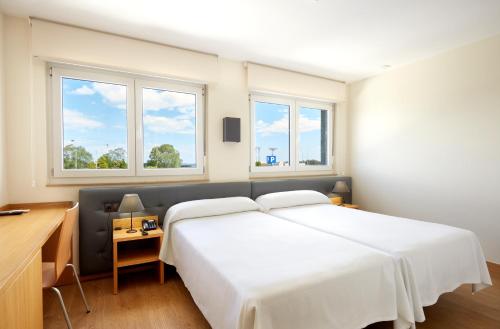 MonteHotel Arias Aeropuerto的卧室设有一张白色大床和两个窗户。