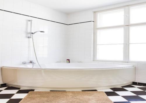 纽约Excellent 3 Bed 1 Bath In Mid East的浴室铺有 ⁇ 格地板,配有白色浴缸。