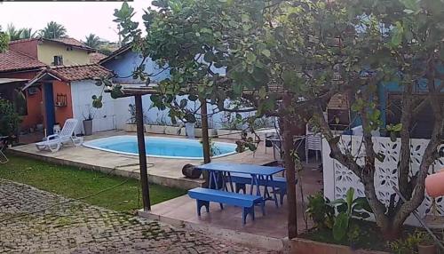 萨夸雷马CASA DA BARRA- Suítes privativas em Saquarema的游泳池旁的野餐桌和长凳