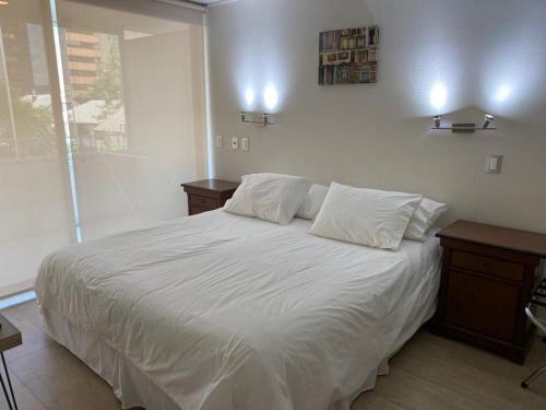 圣地亚哥Kennedy Premium Apartments Colorado的一间卧室配有一张带白色床单的床和两张桌子