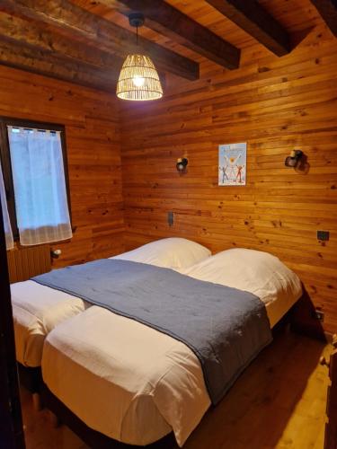 马尼戈Chalet de Manigod的一间带两张床铺的卧室,位于带木墙的房间内