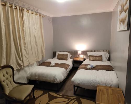 HornchurchSleek 2 bedroom flat-sleeps up to 5 guest的一间卧室配有两张床和椅子