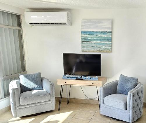 圣胡安KASA Seaview at Coral Beach - Studio for 2 Balcony BEACHFRONT BUILDING POOL的客厅配有两把椅子和一台电视