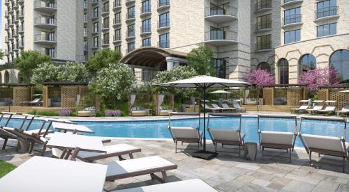 欧文The Ritz-Carlton Dallas, Las Colinas的酒店游泳池配有桌椅和遮阳伞