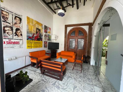 卡利HOSTAL CHONTADURO Casa colonial en pleno centro histórico de Cali- Se alquila la casa entera para 12 o 13 personas o por habitaciones的客厅配有橙色家具和墙上的海报