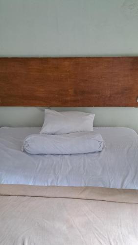 MujurSuburdi Guest House的一张白色的大床,配有木制床头板