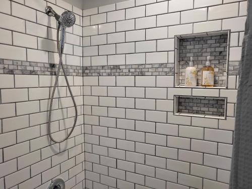 波茨敦Private space, while visiting family this Holiday!的浴室内铺有白色瓷砖并配有软管的淋浴
