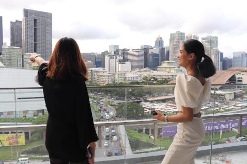 马尼拉Hotel101 - Fort的两个女人站在一座看城市的建筑的顶端