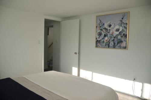 多伦多Entire Basement - 5 Guests 2 Bedrooms 3 Beds的白色卧室,墙上挂有绘画作品