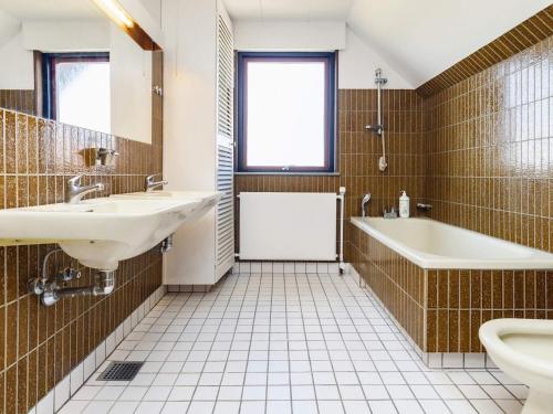 阿森斯Holiday home Assens IX的一间带两个盥洗盆、浴缸和卫生间的浴室