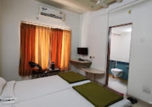BhusāwalHotel Premier - Hotel in Saket Society Bhusawal的一间卧室配有一张床、一张书桌和一台电视