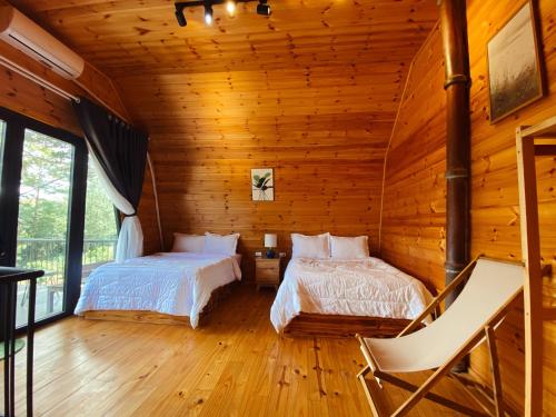 Kon Von KlaT'MĂNG ĐEENG HOMESTAY的小木屋内一间卧室,配有两张床