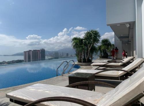 芽庄Scenia Residence Nha Trang的游泳池上的一排躺椅