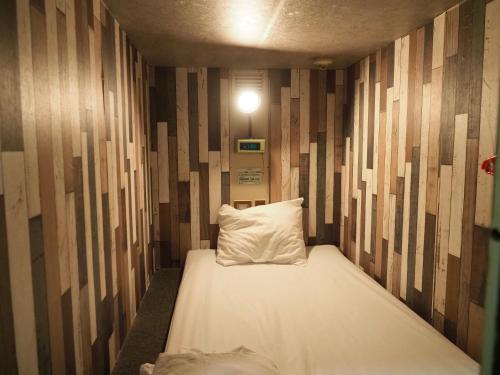 东京Capsule Hotel Block Room的木墙客房中的一张带枕头的床