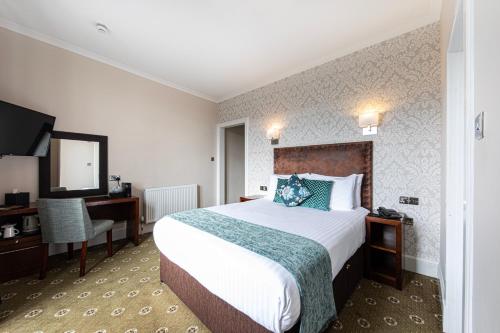 皮特洛赫里Scotland's Spa Hotel的酒店客房配有一张床、一张书桌和一台电视。