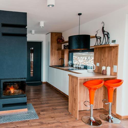 Domek PodMaglem的厨房配有橙色酒吧凳和壁炉