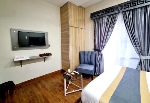 拉合尔Hotel Grand Pakeeza的一间卧室配有一张床、一台电视和一把椅子