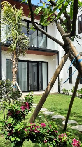 龙目岛库塔VILLA TERAUM的院子内种有棕榈树和鲜花的房子