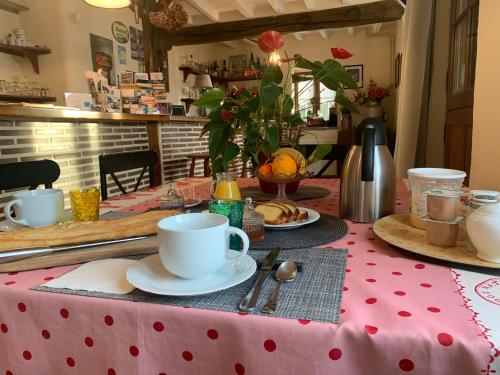 MarchévilleLes Logis du Breuil的一张桌子,上面有红色的波尔卡圆桌布和咖啡杯