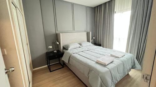 Ban KlangChalong condo的一间卧室配有一张带白色床单的床和一扇窗户。