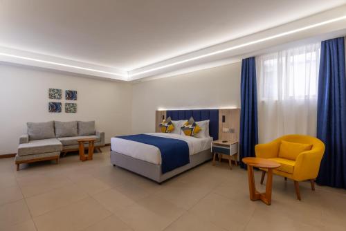 蒙巴萨Premium Inn Mombasa City的一间卧室配有一张床、一张沙发和一把椅子