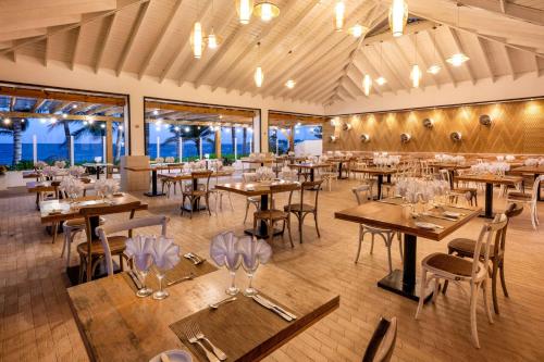 喀巴里特Viva Tangerine by Wyndham, A Trademark All Inclusive的餐厅设有木桌、椅子和窗户。