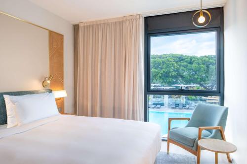 圣丹尼斯Radisson Hotel Saint Denis, La Reunion的酒店的客房 - 带一张床、椅子和窗户
