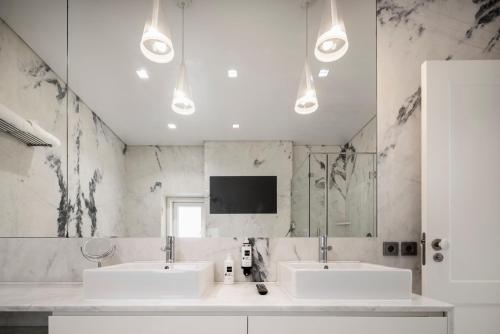 里斯本希亚多特林达德公寓 | 里斯本最佳公寓的一间带两个盥洗盆的浴室和墙上的电视
